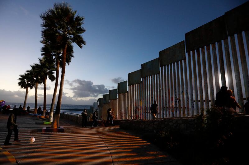 People walk along the US border wall in an oceanside park in Tijuana, Mexico, at sunset. AP