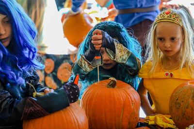 From left, Riley, 8, Harper, 6, and Leighton Fellman, 4, carve pumpkins at the Walking Mountains Science Center's Fright at the Museum in Avon, Colo., Saturday, Oct. 26, 2019. Children were able to carve or draw on pumpkins and take them home. (Chris Dillmann/Vail Daily via AP)