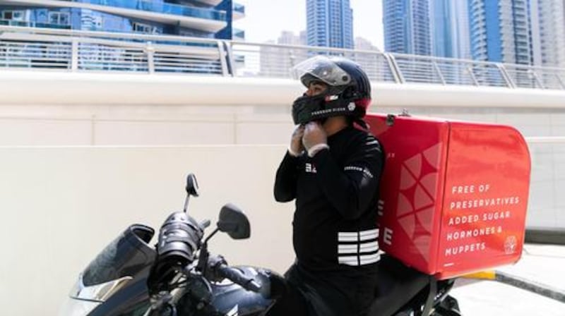 A rider from Freedom Pizza puts on his helmet in Dubai Marina. Mohammed / The National