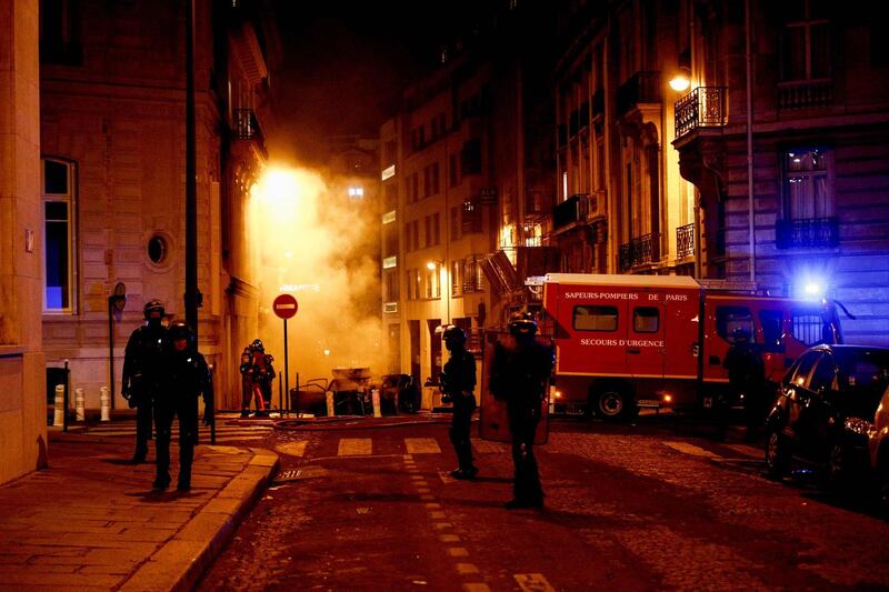 French riot police officers stand next to firefighters putting out a fire near the Champs-Elysees. AFP