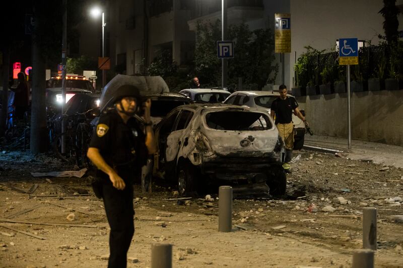 A police officer stands near a burned car at a scene in Tel Aviv. Getty Images