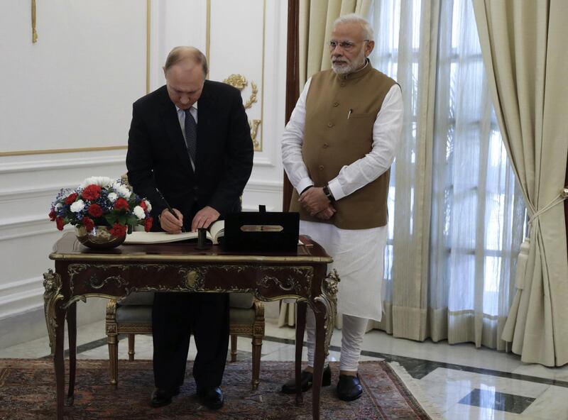 epa07072104 Russian President Vladimir Putin (L) makes a record in the guest book as Indian Prime Minister Narendra Modi (R) looks on at Hyderabad House in New Delhi, India, 05 October 2018. Vladimir Putin is on a two-day official visit in India.  EPA/MIKHAIL METZEL / TASS / KREMLIN POOL / SPUTNIK POOL MANDATORY CREDIT