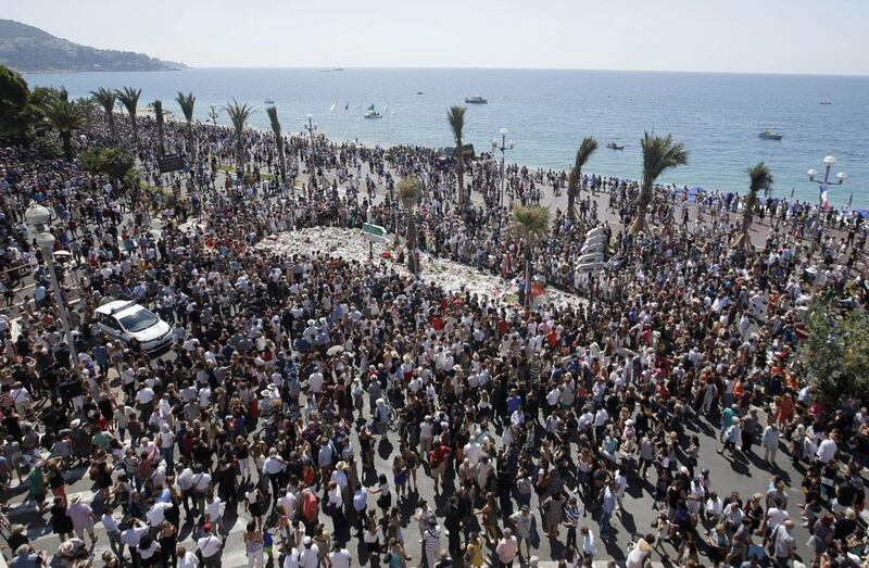 People gather at a makeshift memorial on Nice's famed Promenade des Anglais on July 18, 2016, to observe a minute of silence in memory of those killed in an attack on the seafront area four days before. Luca Bruno/AP Photo