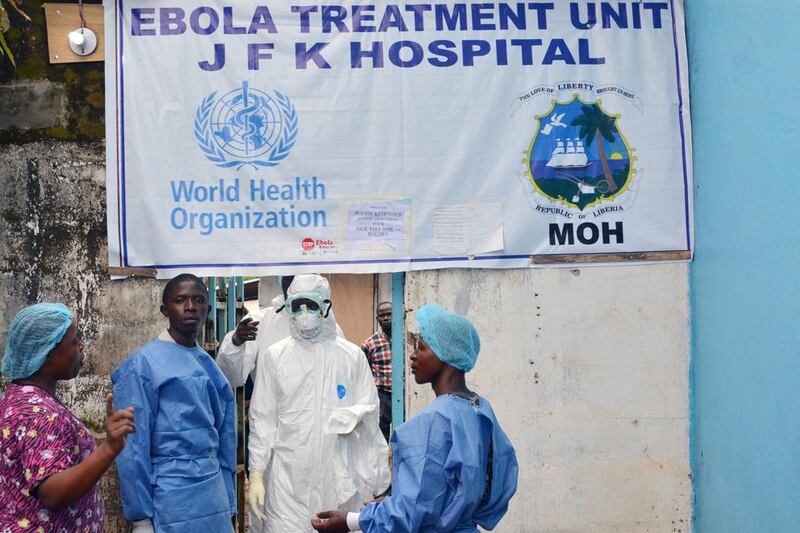 Health workers in protective gear pose at the entrance of the Ebola treatment unit of the John F. Kennedy Medical Center, in the Liberian capital Monrovia, on October 13, 2014. Health workers across Liberia went on strike on Monday to demand danger money to care for the sick at the heart of a raging Ebola epidemic that has already killed dozens of their colleagues. Doctors, nurses and carers in west Africa are on the frontline of the worst-ever outbreak of Ebola, which has killed more than 4,000 people, mostly in Guinea, Sierra Leone and the hardest-hit, Liberia. AFP PHOTO / ZOOM DOSSO