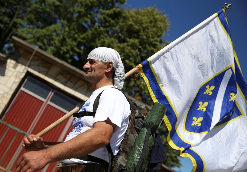 A man carries an old Bosnian flag near the village of Crni Vrh, Bosnia and Herzegovina, July 8, 2020. Hundreds of people started on Wednesday a 85 km march from Nezuk to Srebrenica called the "March of Peace", to retrace the route in reverse taken by Bosnian Muslims who fled Serb forces as they slaughtered 8,000 of their Muslim kin in 1995. The participants in the march consist of survivors of the Srebrenica massacre as well as people from all parts of Bosnia and countries around the world. REUTERS/Dado Ruvic