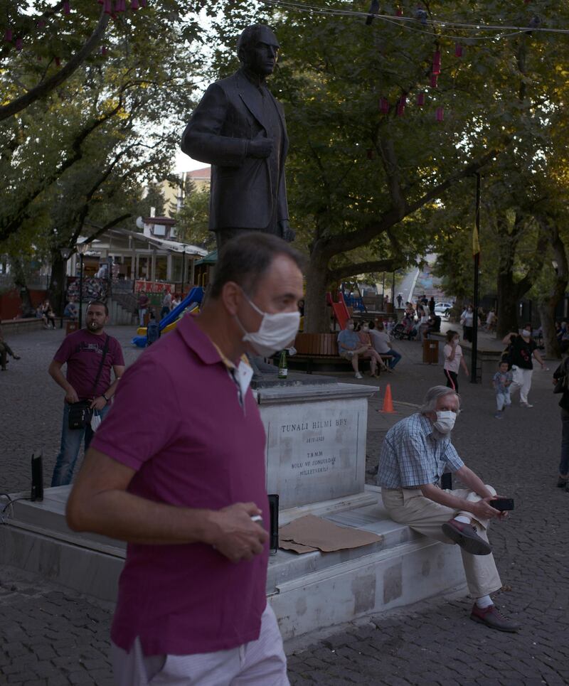 People wearing face masks to protect against the spread of coronavirus, visit a public garden with a statue of Tunali Hilmi Bey, a Turkish intellectual and politician in 1920s, in Ankara, Turkey.  AP Photo