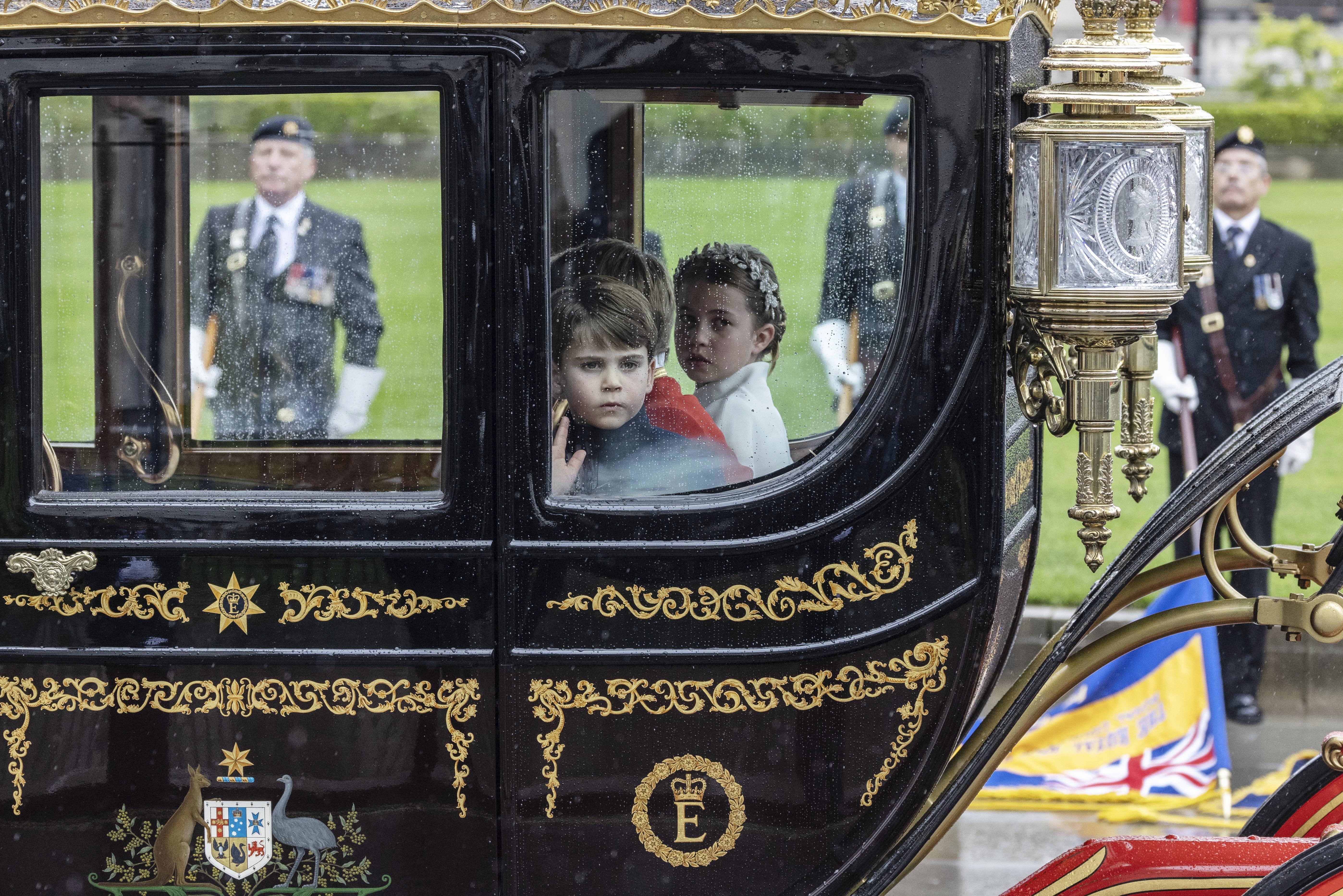 Princess Charlotte, Prince George and Prince Louis sit in a coach as the procession leaves Westminster Abbey following the coronation ceremony of King Charles III and Queen Camilla. AP