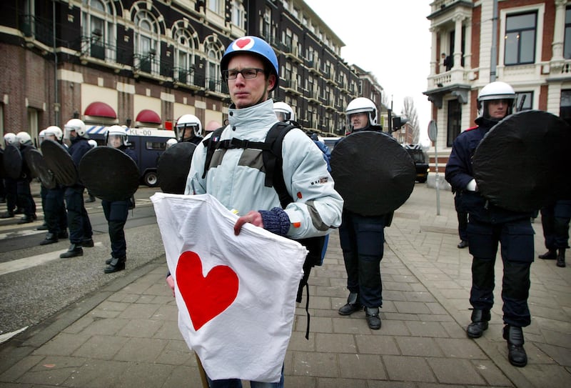 A protester holds a heart flag near riot police in Amsterdam.
