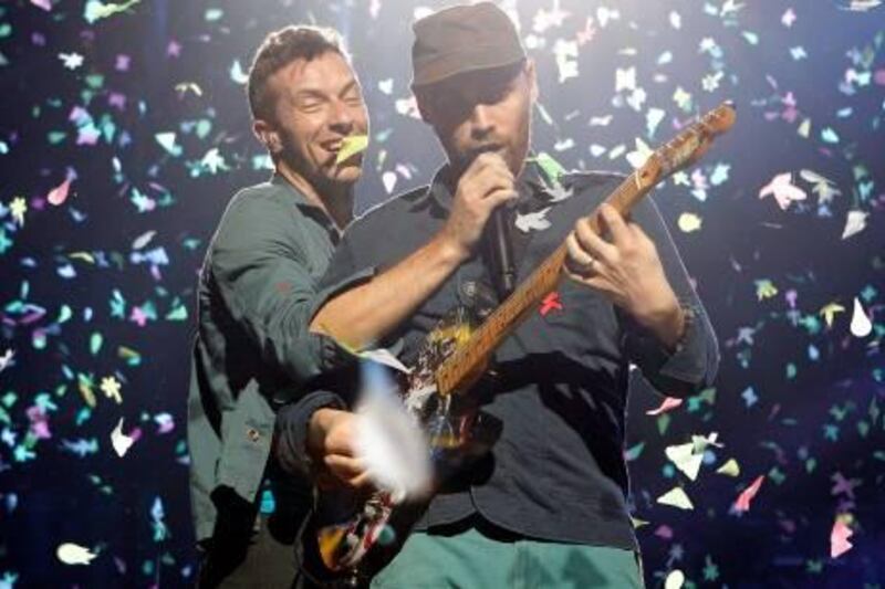 Chris Martin, singer of British alternative rock band Coldplay, left, holds the microphone for Jonny Buckland ,lead guitar, during a performance of the group in Cologne, Germany, Thursday Dec. 15, 2011.  (AP Photo/dapd/Roberto  Pfeil) *** Local Caption ***  Germany Music Coldplay.JPEG-04284.jpg