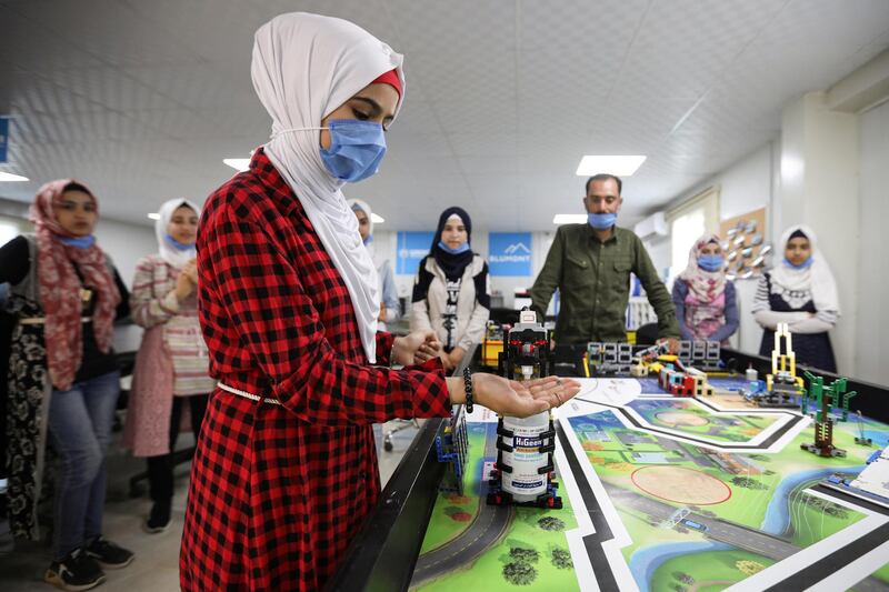 Syrian refugee students and instructor Yasine Hariri use a robot prototype that automatically dispenses sanitiser during a UNHCR-led Innovation Lab program, at the Zaatari refugee camp in the Jordanian city of Mafraq. Reuters