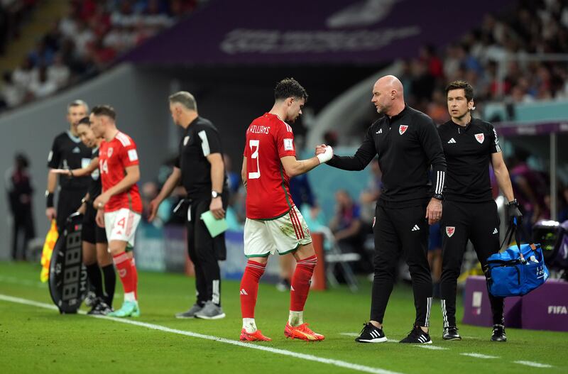 Wales' Neco Williams with manager Rob Page as he leaves the pitch after a suspected concussion. PA