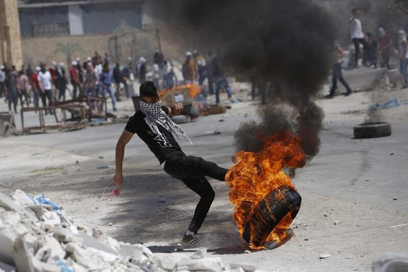A Palestinian kicks a burning tire during clashes with Israeli forces following a rally in support of hunger-striking prisoners in Israeli jails, in the West Bank village of Beita, southeast of Nablus city, Friday, April 28, 2017. Majdi Mohammed /AP 