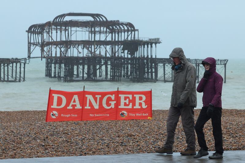A couple walk past a public information sign on the beach ahead of the arrival of the storm, in Brighton. Reuters