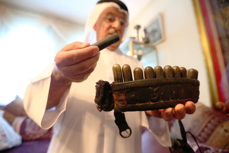 Dr Ahmed Khoori with a belt, dating from about the 1830s, and brass containers packed with the correct combination of shot and powder to allow quick reloading of a flintlock rifle. Fatima Al Marzooqi / The National