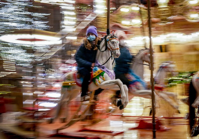 A girl wearing a face mask rides on a merry-go-round at the Christmas market in Frankfurt, Germany. AP Photo