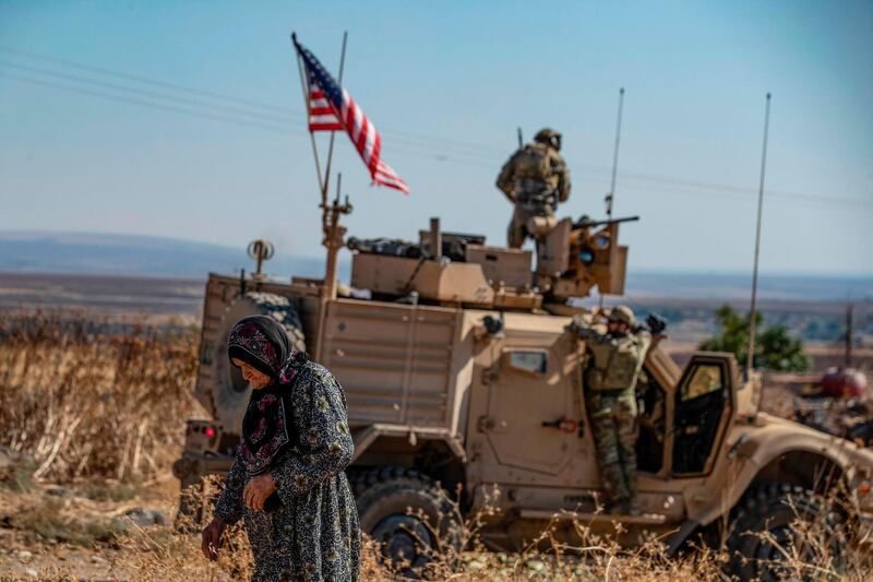 A Syrian elderly woman walks past a US armoured vehicle on a patrol in the village of Ein Diwar in Syria's northeastern Hasakeh province. AFP