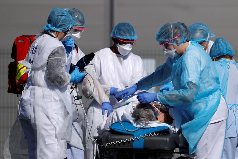 French rescue team wearing protective suits carry a patient on a stretcher from Mulhouse hospital. Reuters