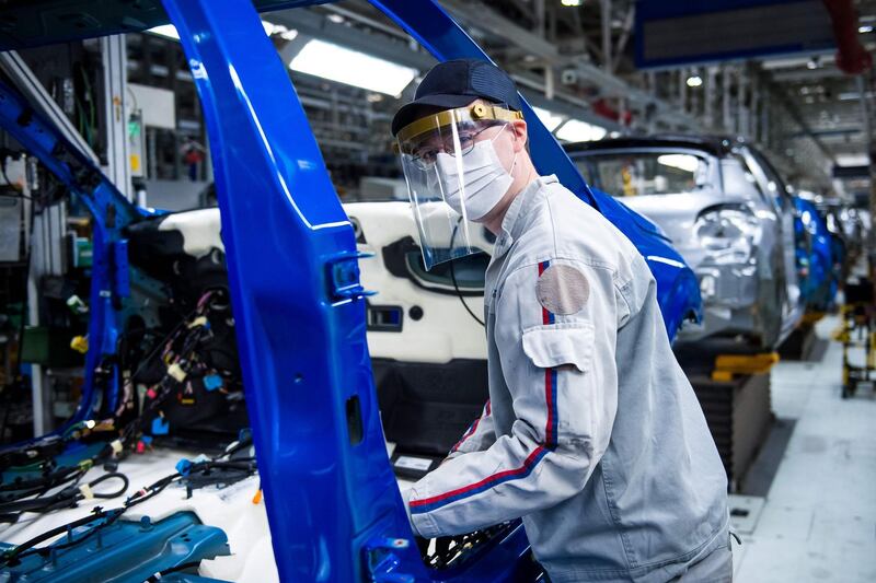 An employee demonstrates precautionary measures on the assembly line at the PSA Peugeot Citroen plant in Trnava, Slovakia. AFP