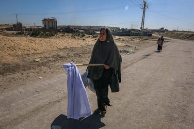 A displaced Palestinian woman carries a white flag after passing an Israeli tank while fleeing an area near Khan Younis, Gaza. Bloomberg