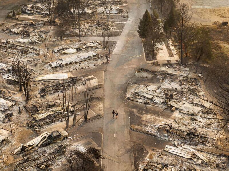 People walk through a mobile home park destroyed by fire in Phoenix, Oregon. AFP