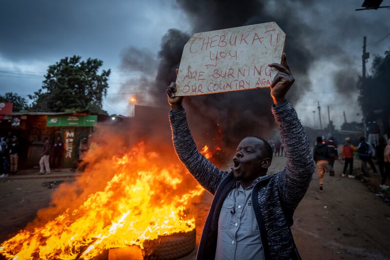 A supporter of presidential candidate Raila Odinga holds a placard referring to electoral commission chairman Wafula Chebukati, while shouting "No Raila, No Peace", in Kibera. AP