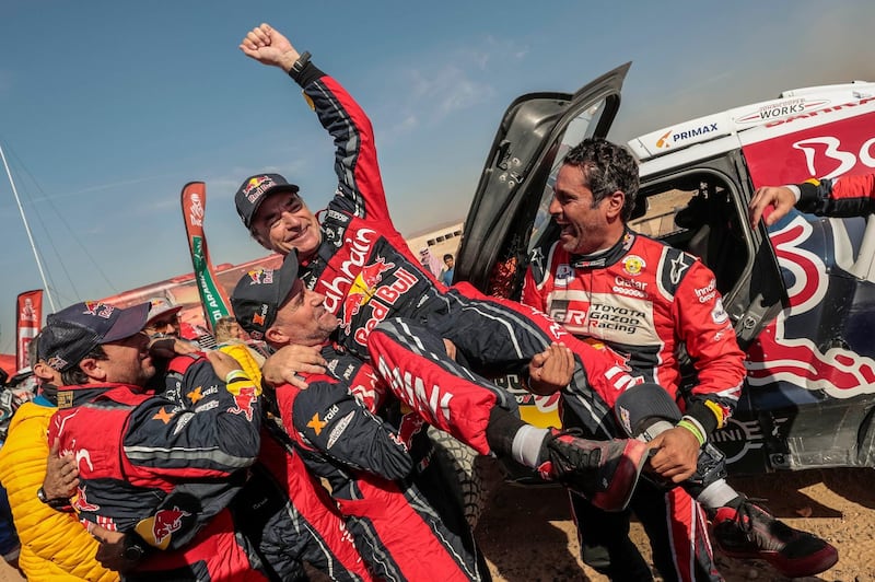 Carlos Sainz, of Spain is lifted in the air by fellow drivers Nasser Al-Attiyah and Stephane Peterhansel after sealing victory in the Dakar Rally on Friday. AP