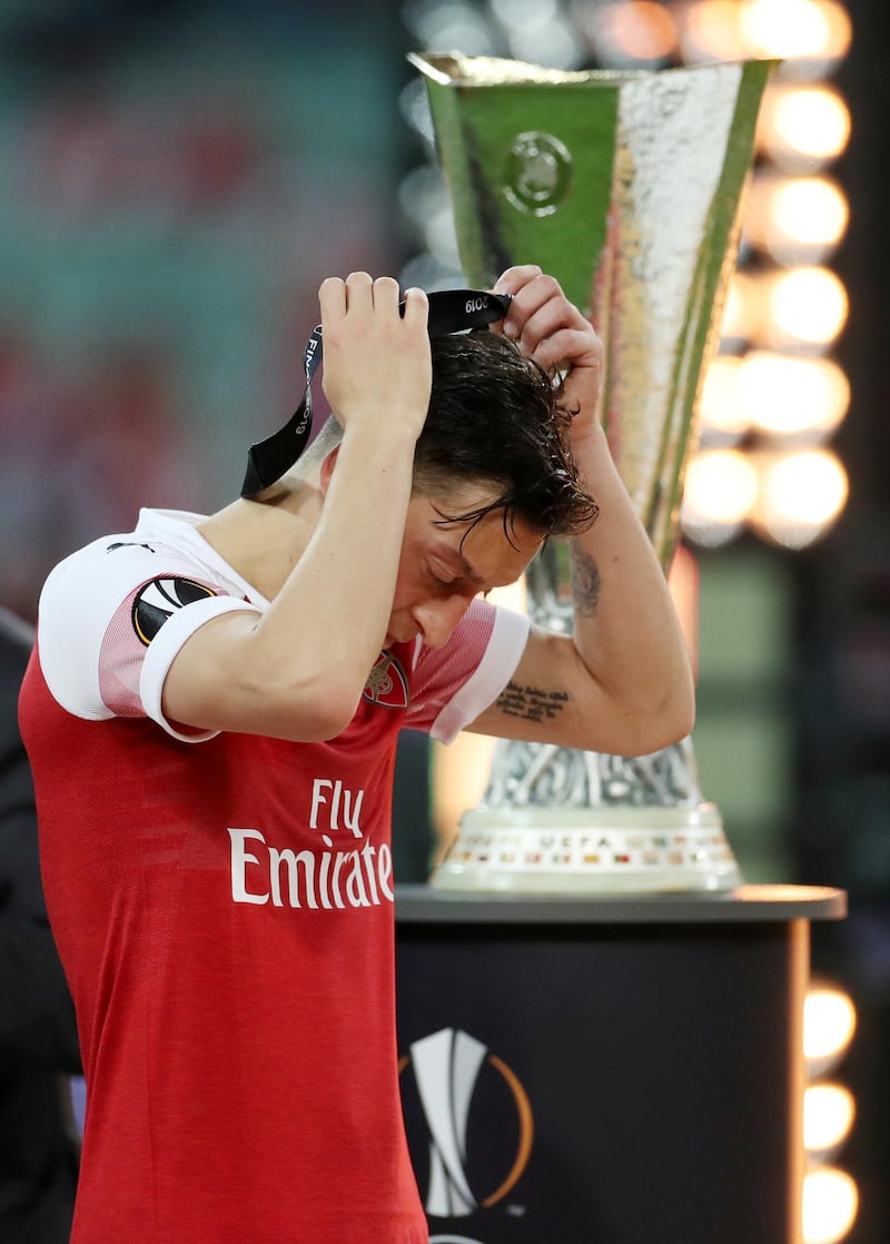 Arsenal's Mesut Ozil removes his medal as he walks past the trophy after the match. REUTERS.