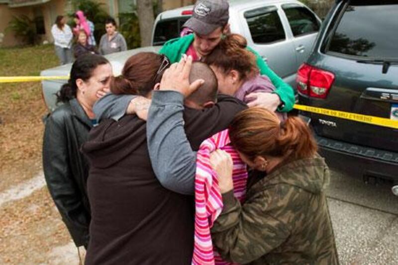 Jeremy Bush, center with hand on head, is embraced by family and friends outside his home on Friday after his brother fell down a sinkhole under their house. AP Photo