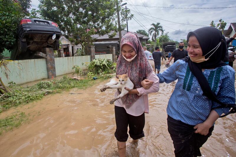 An Indonesian woman carries a stray cat which was rescued from an area affected by floods in Medan, North Sumatra, Indonesia. Torrential rains in the country's third-largest city swelled rivers and flooded thousands of homes, leaving a number of people killed and missing. AP Photo