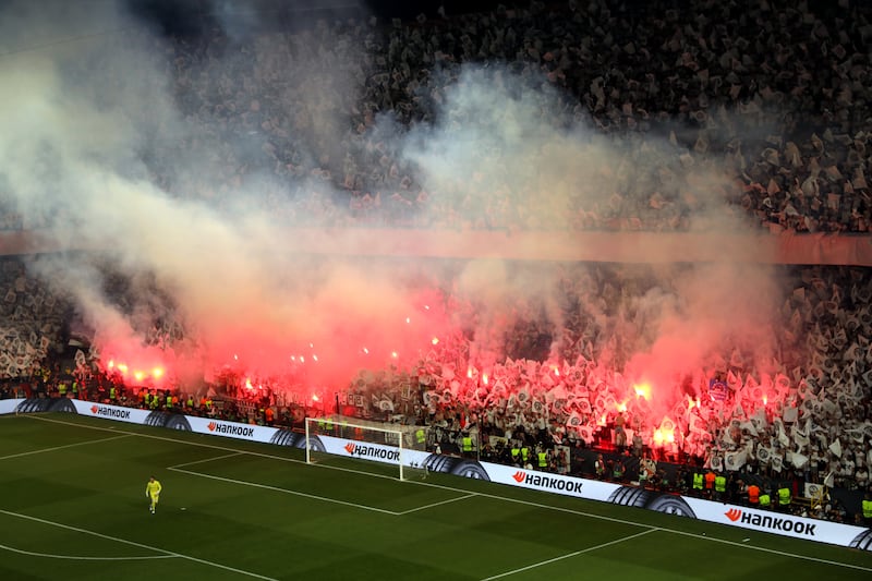 Eintracht Frankfurt fans let off flares in the stands. PA