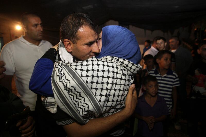 A released Palestinian prisoner Hosni Sawalha, left, is hugged upon his arrival to his family house in in Azmout village near Nablus in the West Bank .Wednesday, Aug. 14, 2013. Israel released 26 Palestinian inmates, including many convicted in grisly killings, on the eve of long-stalled Mideast peace talks, angering families of those slain by the prisoners, who were welcomed as heroes in the West Bank and Gaza. (AP Photo / Nasser Ishtayeh) *** Local Caption ***  Mideast Israel Palestinians.JPEG-03226.jpg