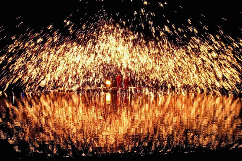 Sparks are created as molten iron is thrown against cold bricks at the Zhuang Song Festival, also known as San Yue San, in Liuzhou, in south-western China. AFP