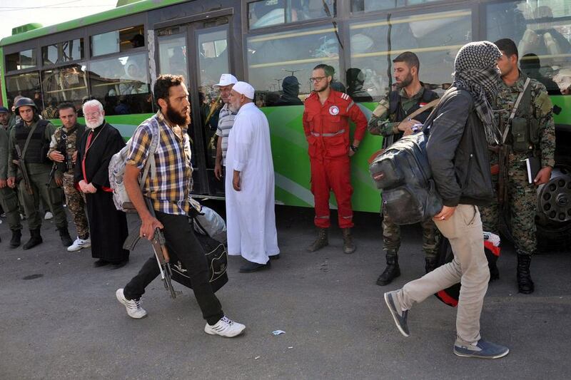 Syrian soldiers and a member of the Syrian Arab Red Crescent watch as rebel fighters board a bus to evacuate the besieged Waer district of Homs on September 26, 2016. Sana/Handout via Reuters 