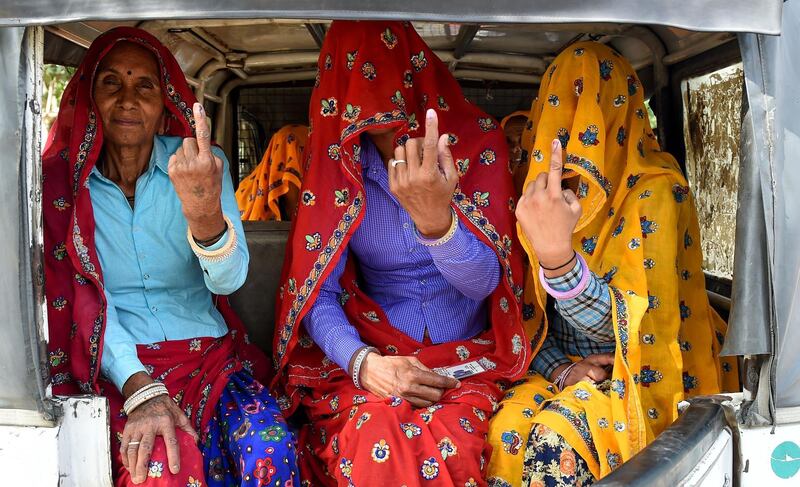 Indian women sit inside an auto-rickshaw as they show their ink-marked finger after casting their vote during the fifth phase of India's general election in Alwar in the northern Indian state of Rajasthan on May 6, 2019.  / AFP / Money SHARMA
