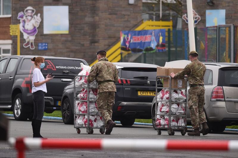 An NHS worker speaks with soldiers as they carry supplies at Pontins. AFP