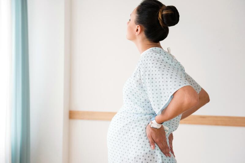 Pregnant Caucasian with back pain in hospital gown