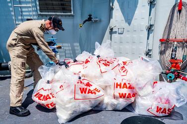 A crew member of 'HMCS Calgary' inspects contraband seized during a counter-smuggling operation on April 24, 2021. DND / MDN Canada