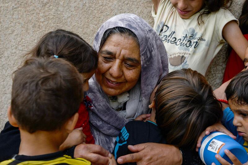 Sana Ibrahim (C), a 61-year-old Iraqi matriarch and caretaker for 22 grandchildren, embraces her family members in a courtyard in their home in the northern city of Mosul on August 14, 2018. - Despite the Islamic State group being driven from Mosul, 61-year-old Sana Ibrahim faces daily hardship in looking after her 22 grandchildren and her Alzheimer's-ridden septuagenarian husband, after losing her four sons and son-in-law to the jihadists during their occupation. (Photo by Zaid AL-OBEIDI / AFP)