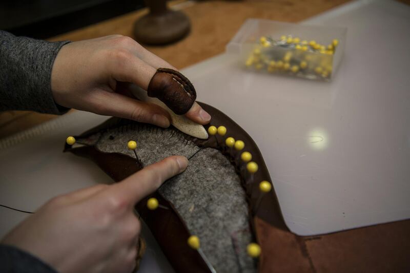 A craftsman stitches a piece of leather on a saddle at the French luxury brand Hermes' saddlery in Paris on March 11, 2019. - Since 1880, Hermes has been making sports and leisure saddles in its original workshops on the rue du Faubourg Saint-Honore in central Paris. Today 23 artisans make around 400 saddles each year. (Photo by Christophe ARCHAMBAULT / AFP)