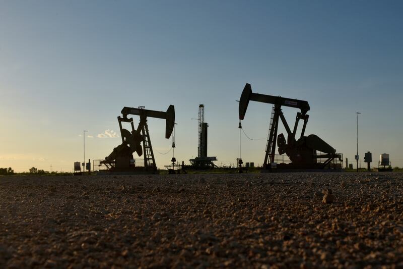 Pump jacks operate in front of a drilling rig in Texas. Oil prices have been supported by looming sanctions on Russian crude. Photo: Reuters