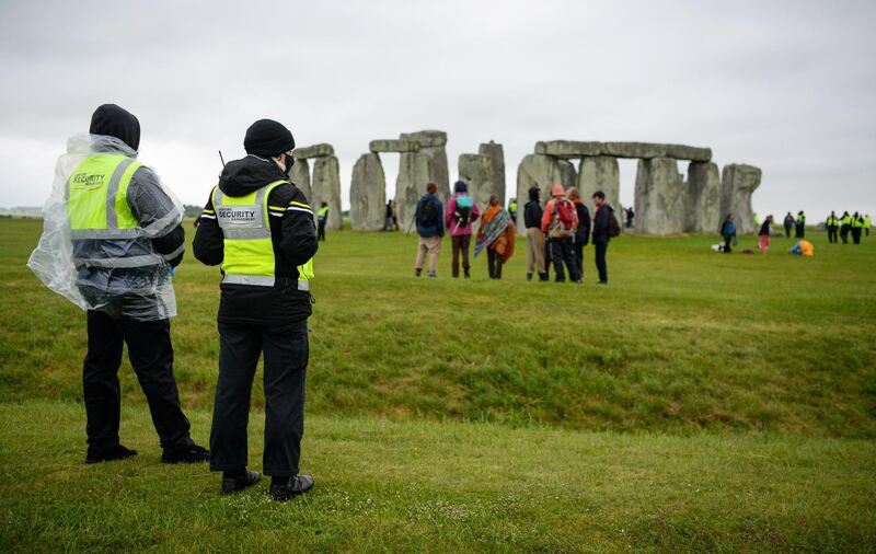 AMESBURY, ENGLAND - JUNE 21: Security guards look on after a large number of people enter the closed site at Stonehenge on June 21, 2021, in Amesbury, United Kingdom. English Heritage, which manages the site, said, 'With this week's news that the Government is delaying the lifting of the remaining Covid-19 restrictions on 21 June we have taken the difficult decision to cancel the planned Summer Solstice celebrations at Stonehenge this year'. (Photo by Finnbarr Webster/Getty Images)