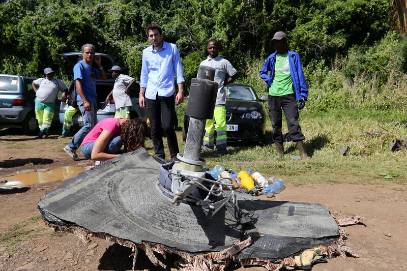 Local ecological association members and volunteers stand behind debris found on August 11, 2015 in the eastern part of Sainte-Suzanne, on France's Reunion Island in the Indian Ocean, during search operations for the missing MH370 flight conducted by French army forces and local associations. The hunt for more wreckage from the missing MH370 resumed on Reunion island on August 9 after being suspended due to bad weather, local officials said.  A wing part was found on the island in late July and confirmed by the Malaysian prime minister to be part of the Boeing 777 which went missing on March 8, 2014 with 239 people onboard. AFP PHOTO / RICHARD BOUHET / AFP PHOTO / RICHARD BOUHET