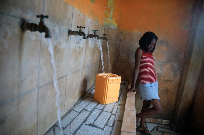 With no running water at home, a woman fills a container at a water fill station in Port-au-Prince, Haiti. AP Photo