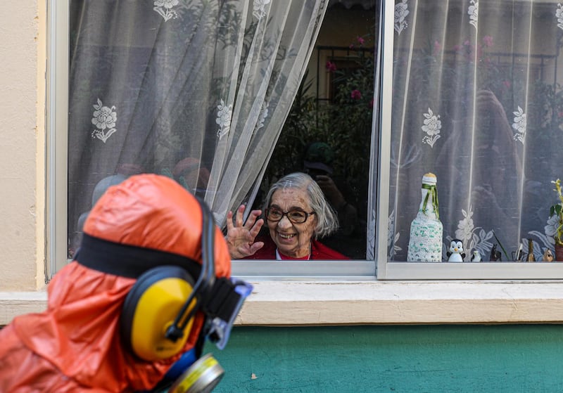 A woman waves to a city worker dressed in a hazmat suit as he disinfects the streets in her neighborhood as a precaution against the spread of the new coronavirus, in Santiago, Chile. AP Photo