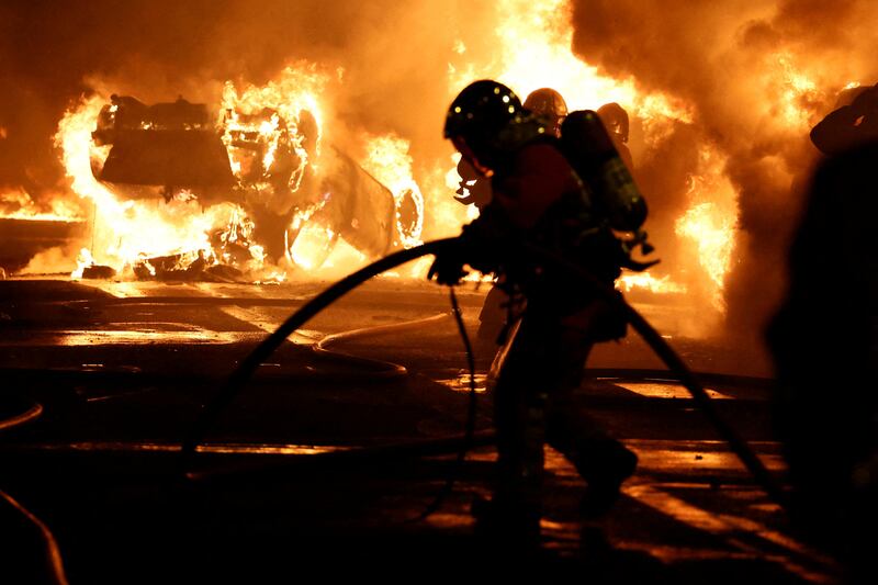 Firefighters extinguish burning vehicles during clashes between protesters and French police on June 29. Reuters
