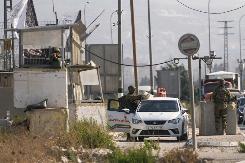 Israeli soldiers check a Palestinian car at the Hawara checkpoint in the occupied West Bank on Saturday after two Israelis were shot dead in the town. AP Photo