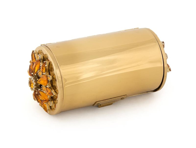 A gold metal minaudière with a citrine crystal floret embellishment features three compartments, including one for loose powder with a cotton buffer, mirror and comb. Courtesy Julien’s Auctions