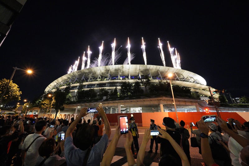 People gather near the National Stadium to watch the fireworks during the closing ceremony of the Tokyo Olympics.