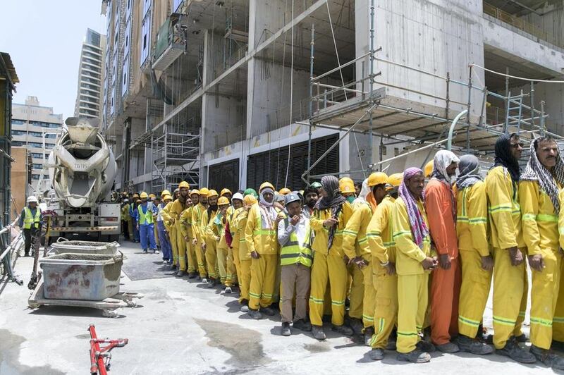 Volunteers of the Ramadan Sharing Fridges initiative hand out hundreds of environmentally friendly bags filled with food and cold drinks to construction workers who labour in intensely hot temperatures. Reem Mohammed / The National