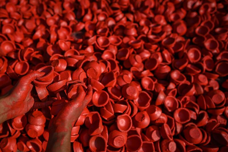 A street vendor dyes earthen lamps in New Delhi. AFP